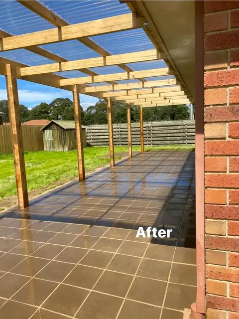 Timber pergola over a paved area beside a brick home